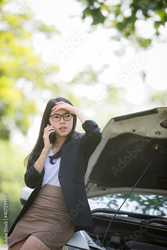 Asian business woman sad waiting for help by a broken car. Use a mobile phone to call the mechanic. © NITIKAN T.