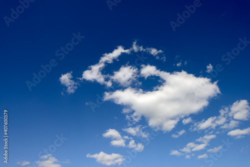 White fluffy clouds illuminated by sunlight against a blue sky