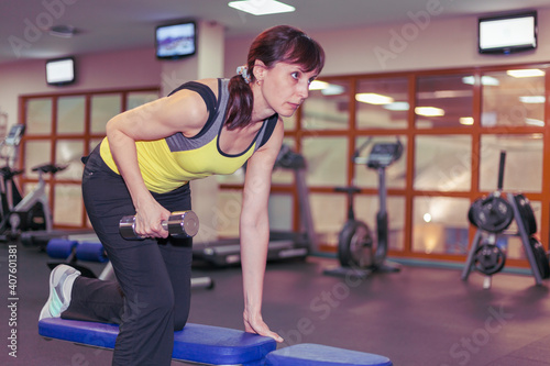 fitness hall, the girl is engaged on the simulators, woman doing exercises with dumbbells