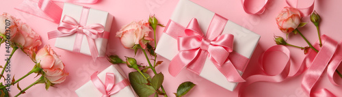Concept of Valentine's day with gift boxes and roses on pink background