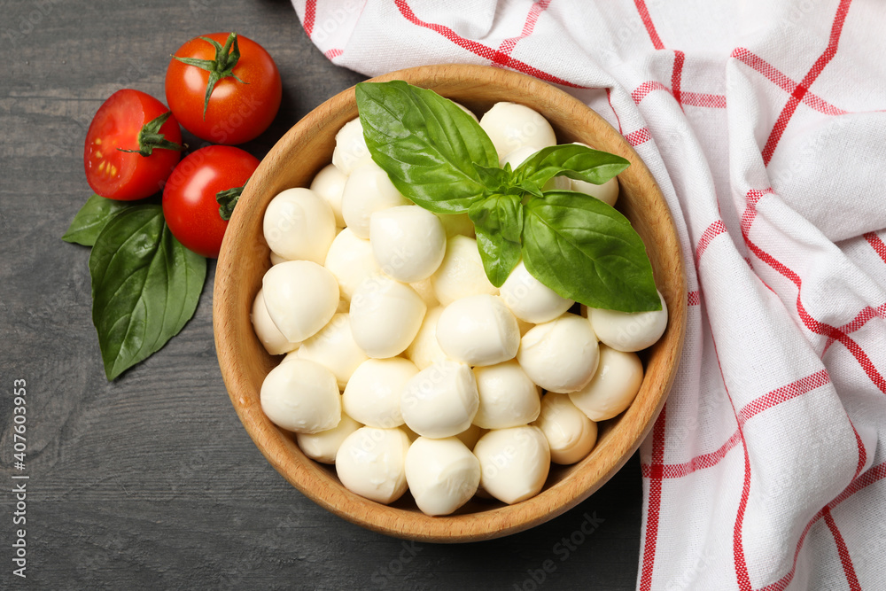 Bowl with mozzarella and basil, tomato and towel on dark wooden background, top view Bowl with mozzarella and basil, tomato and towel on dark wooden background, top view