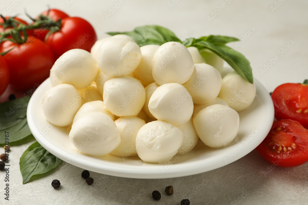 Plate with mozzarella and basil, tomato and pepper on white textured background, close up