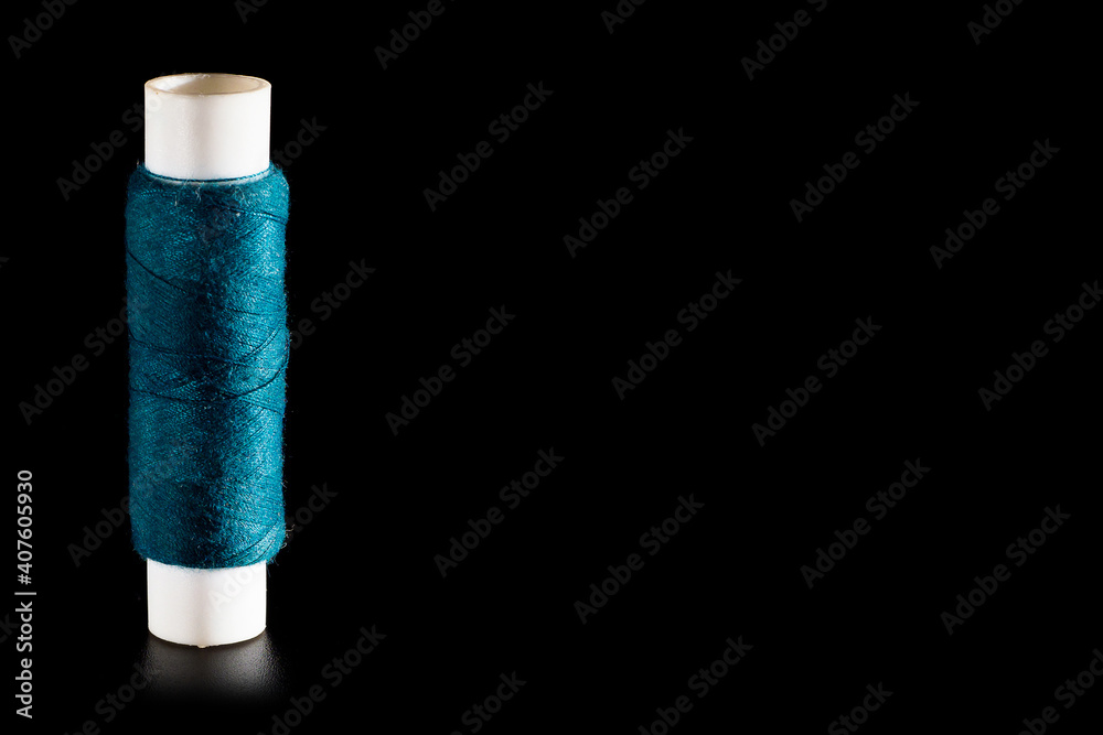 Reel with green sewing silk threads isolated on a black background, close-up, copy space. Bright background for sewing and needlework Reel with green sewing silk threads isolated on a black background, close-up, copy space. Bright background for sewing and needlework