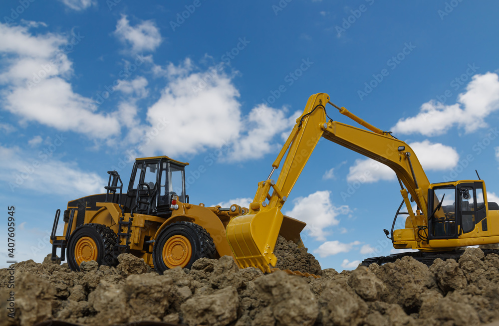 Excavator and Wheel loader are digging the soil in the construction site on the blue sky background Excavator and Wheel loader are digging the soil in the construction site on the blue sky background