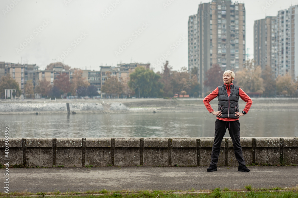 Active senior woman stretches her muscles before running through the city during the day. Active senior woman stretches her muscles before running through the city during the day.