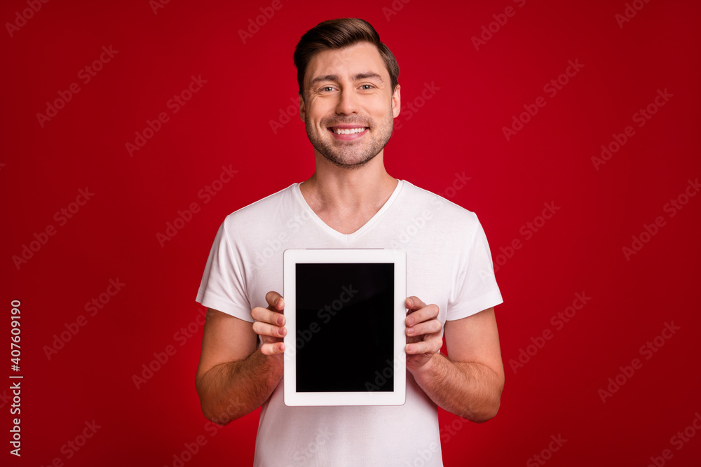Photo of cheerful young guy toothy smile hands hold demonstrating display isolated on maroon color background Photo of cheerful young guy toothy smile hands hold demonstrating display isolated on maroon color background