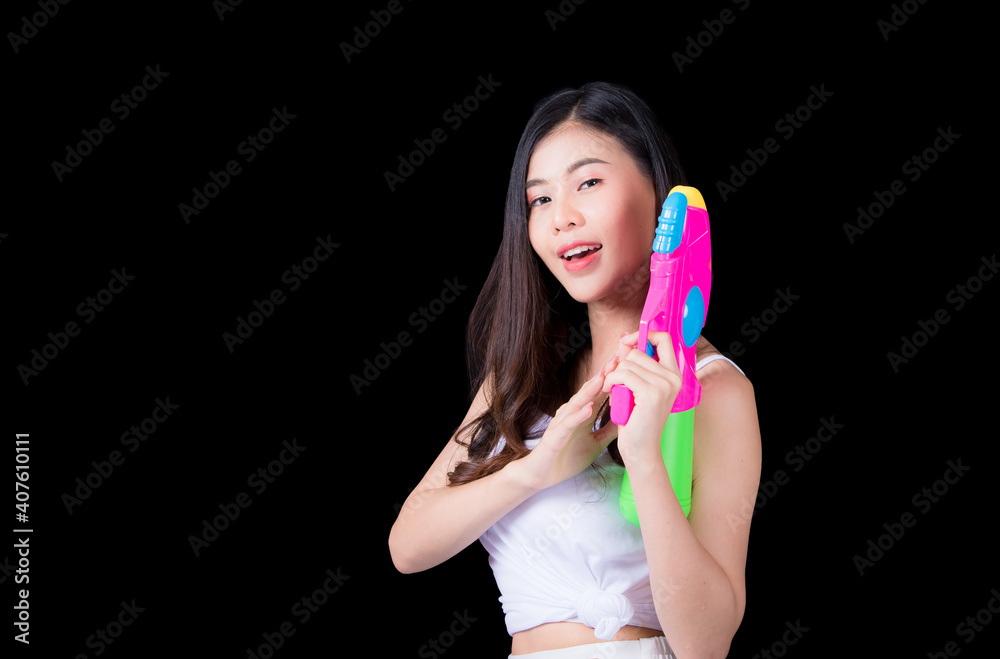 Portrait cheerful young asian woman Wearing a yellow tank top ,holding plastic water gun Smiling and having fun playing in the water Songkran festival, Songkran Thailand. isolated on black background. Portrait cheerful young asian woman Wearing a yellow tank top ,holding plastic water gun Smiling and having fun playing in the water Songkran festival, Songkran Thailand. isolated on black background.