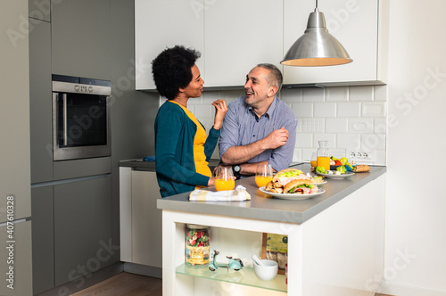 Mid adult couple standing in the kitchen preparing sandwich for breakfast at home.