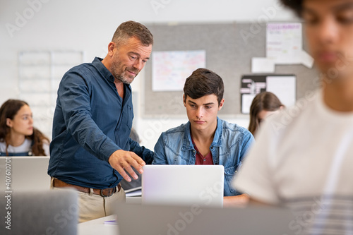 Professor helping student during computer class photo