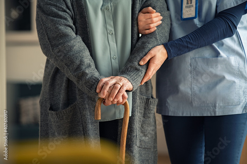 Nurse assisting senior with walking cane photo