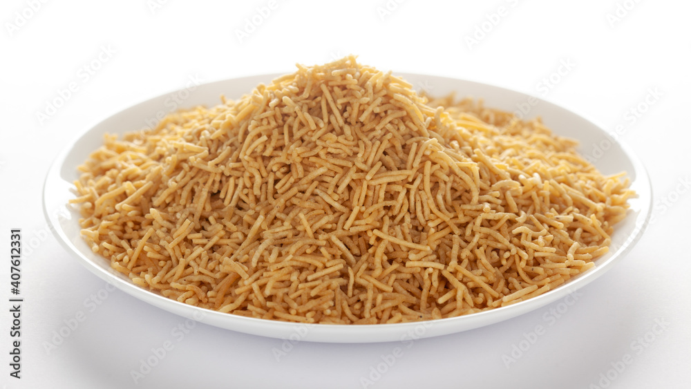 Indian spicy snacks (Namkeen) - Bikaneri Besan Bhujia in a white plate, made with chickpea flour (Besan), side view, against the white background. Indian spicy snacks (Namkeen) - Bikaneri Besan Bhujia in a white plate, made with chickpea flour (Besan), side view, against the white background.