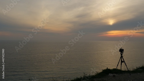 Camera taking picture of sunset over sea