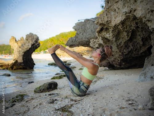 Outdoor yoga practice. Attractive woman practicing Ubhaya Padangusthasana, Wide-Angle Seated Forward Bend. Strengthen legs and core. Self care concept. Yoga retreat. Bali, Indonesia photo