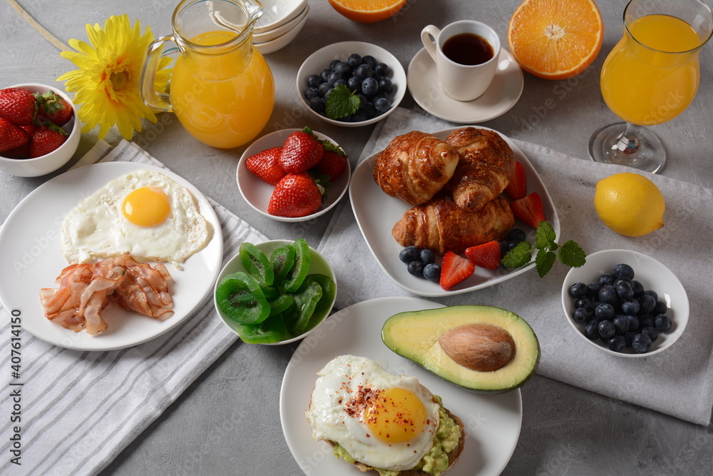 Healthy breakfast. Toast with avocado and egg, bacon and eggs, fresh and dried fruits, fresh juice
