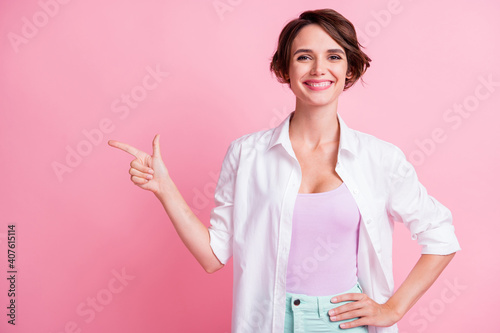 Photo of happy young woman hold hand waist wear white shirt point empty space isolated on pink color background