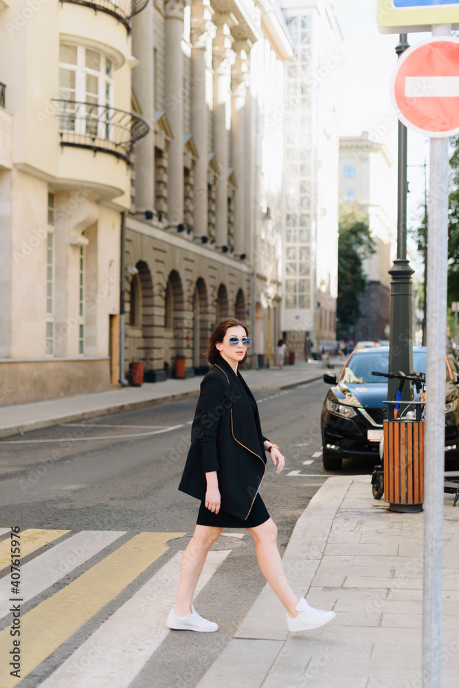 Beautiful woman in a black dress on a background of an urban landscape