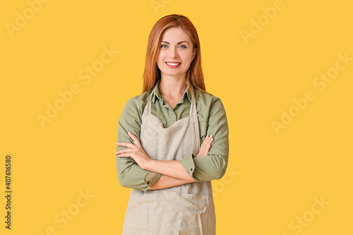Beautiful young woman wearing apron on color background