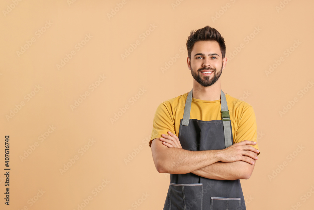 Young man wearing apron on color background Young man wearing apron on color background