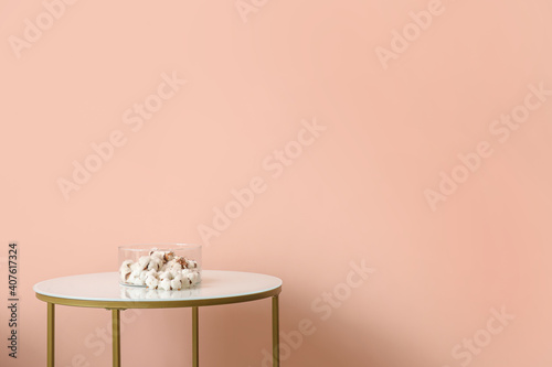 Stylish table with cotton flowers near color wall
