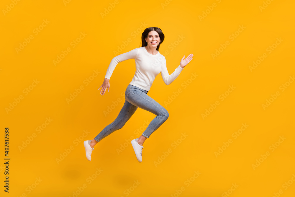 Full size profile photo of optimistic girl jump run wear sweater jeans sneakers isolated on yellow color background