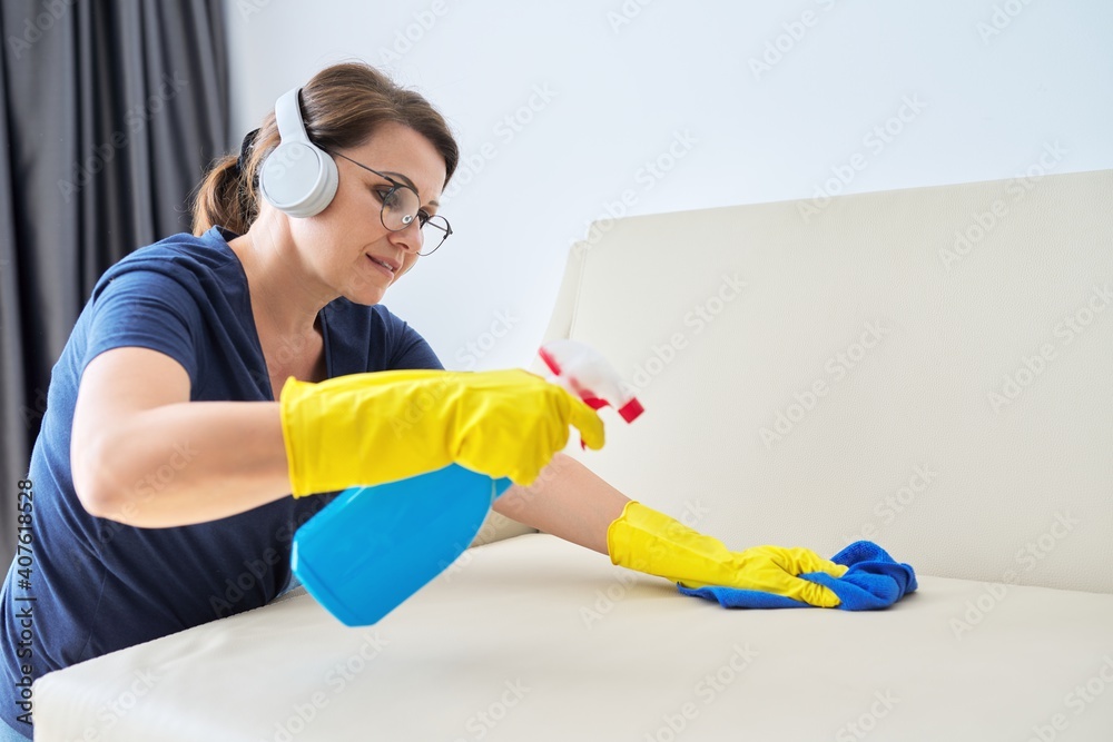 Woman doing house cleaning, female in headphones and gloves with detergent