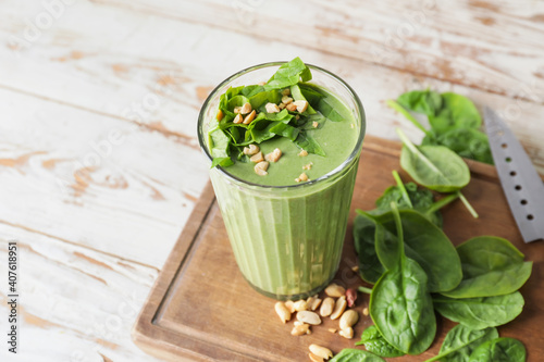 Glass of healthy spinach smoothie on wooden background