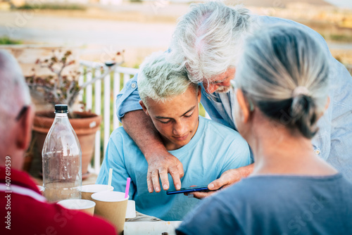 Fotografie Grandfather explain smart phone use to her grandson teenager boy - group of peop