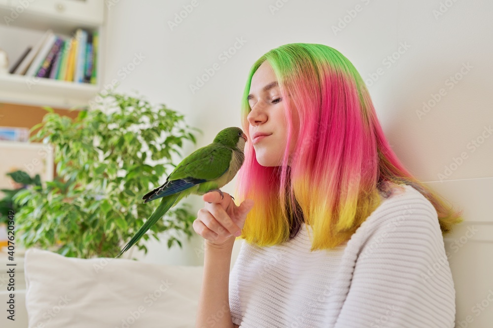 Teenager girl kissing a parrot. Close-up face of woman and green quaker parrot