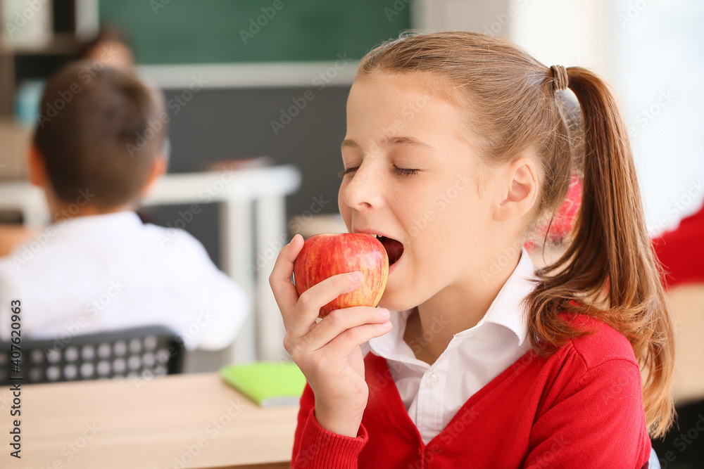 Schoolgirl eating apple in classroom Schoolgirl eating apple in classroom