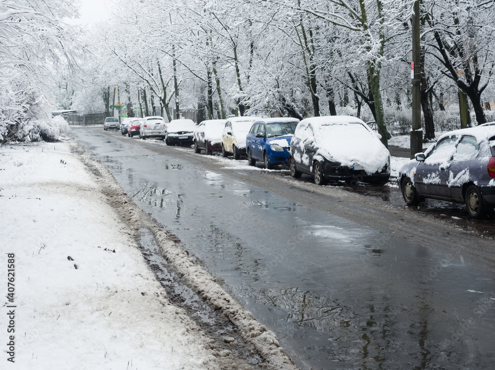 Fototapeta premium Snowy cars standing along the street. Winter cityscape. Snow-covered cars