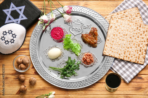 Passover Seder plate with traditional food, Torah and Jewish cap on table