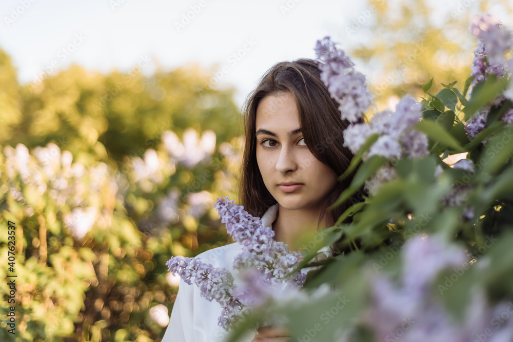 portrait of a young attractive girl on a background of green foliage and lilac flowers. woman in nature portrait of a young attractive girl on a background of green foliage and lilac flowers. woman in nature