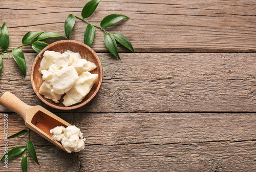 Fotografie Plate and scoop with shea butter on wooden background