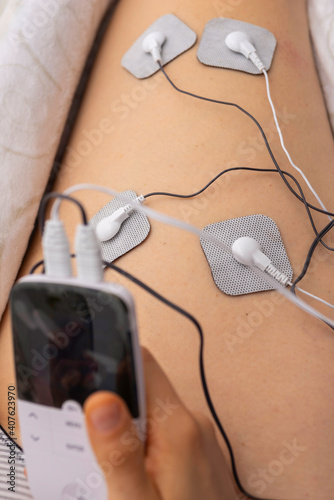 Someone using an electrostimulator on one leg. photo