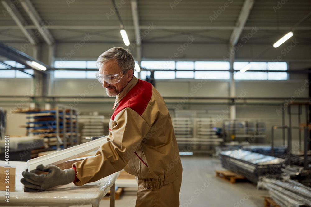 Happy mid adult carpenter working at his workshop.