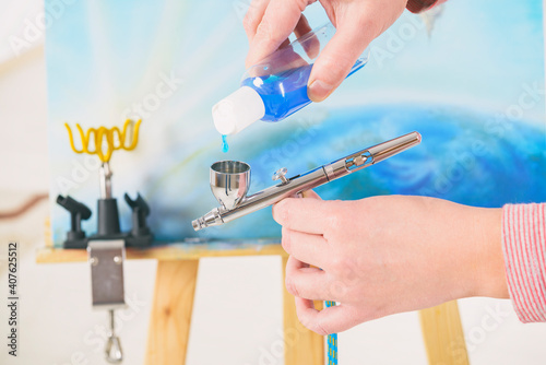 Artist fills the airbrush canister with blue paint