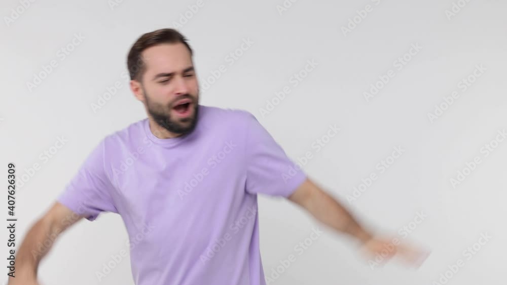 Cheerful bearded young man 20s in basic violet t-shirt isolated on white background studio. People lifestyle concept. Dancing doing dab hip hop dance hands move gesture youth sign hiding covering face Cheerful bearded young man 20s in basic violet t-shirt isolated on white background studio. People lifestyle concept. Dancing doing dab hip hop dance hands move gesture youth sign hiding covering face