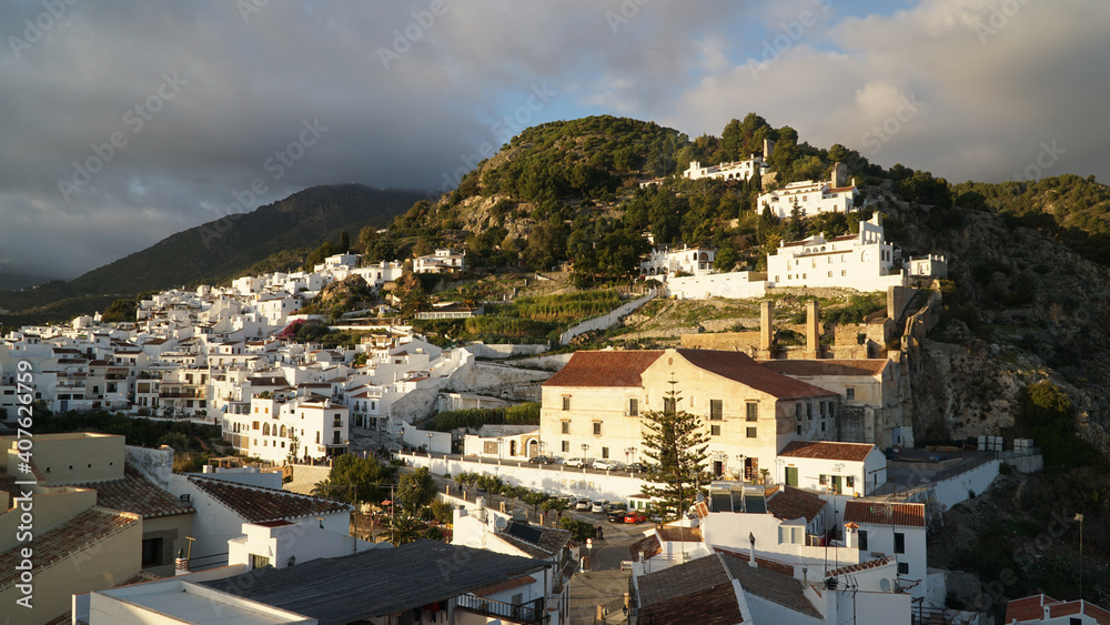 White houses during sunset in Nerja Village, located within a green hill landscape in Andalusia, Spain.