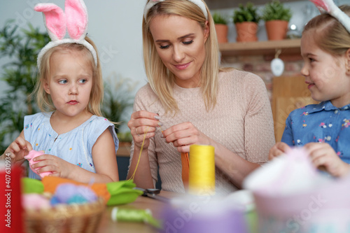 Mother and daughters preparing Easter decorations at home © gpointstudio