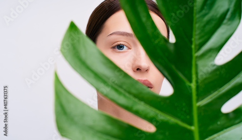 Beautiful young woman with green monstera leaf.