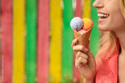 Happy young woman with delicious ice cream in waffle cone outdoors, closeup. Space for text