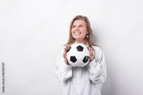 Portrait of charming young woman smiling and holding soccer ball over white background. © Vulp