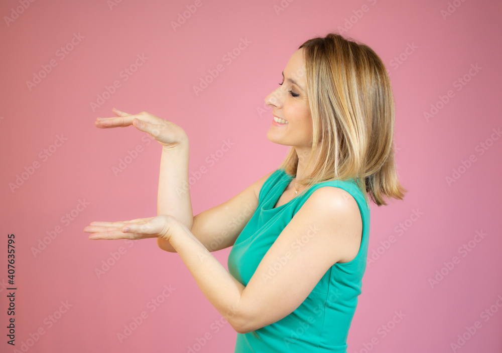 Portrait of smiling woman showing something or copy space for product or sign text, isolated over pink background Portrait of smiling woman showing something or copy space for product or sign text, isolated over pink background