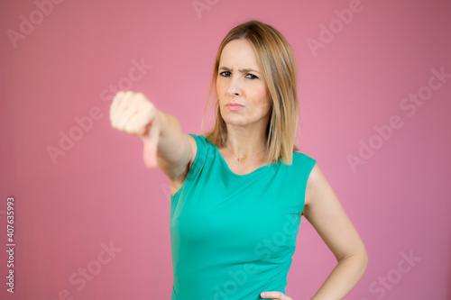 Portrait of displeased woman who is showing thumb down