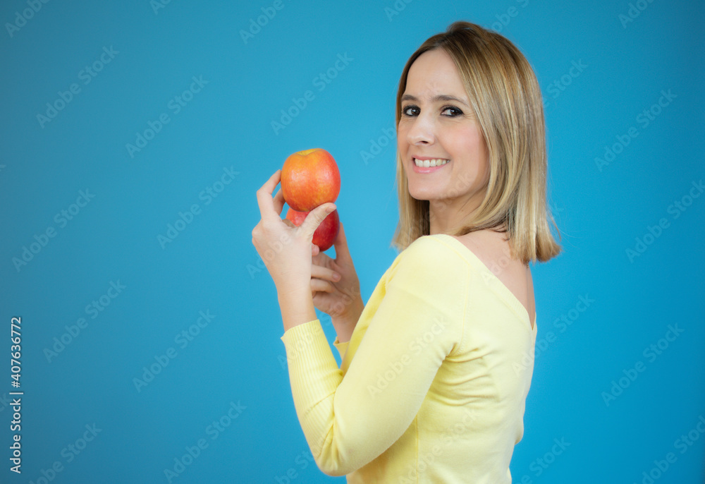 Happy beautiful woman holding two apples isolated over blue background