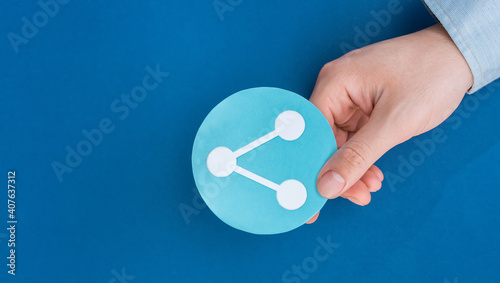 Male hand holding sharing shape symbol, on blue background.