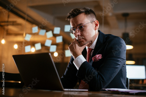 Young businessman using laptop in his office. Handsome man working at his workplace..