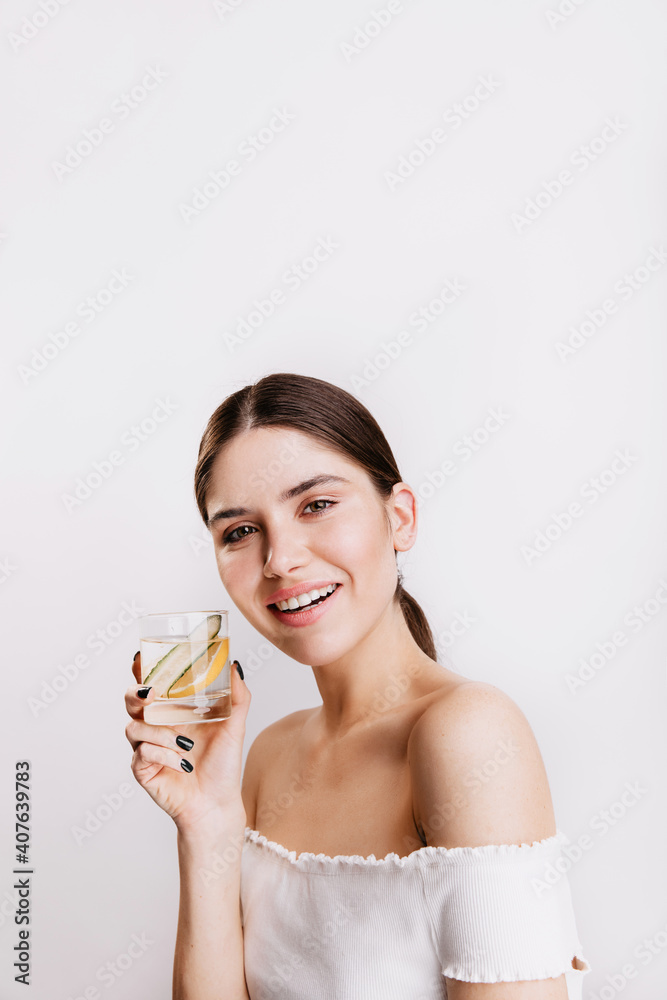 Attractive dark-haired woman is full of energy and smiles. Lady holding glass of water with lemon Attractive dark-haired woman is full of energy and smiles. Lady holding glass of water with lemon