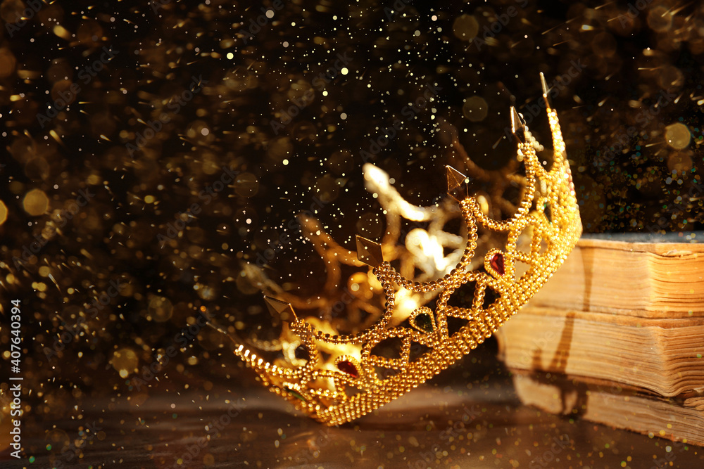 Fantasy world. Beautiful golden crown and old books on table, bokeh effect Fantasy world. Beautiful golden crown and old books on table, bokeh effect