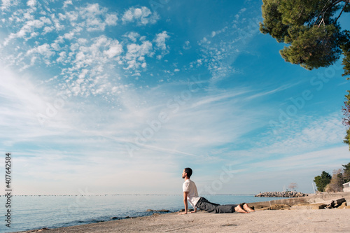 Attractive young man practicing yoga meditation and breathwork outdoors by the sea